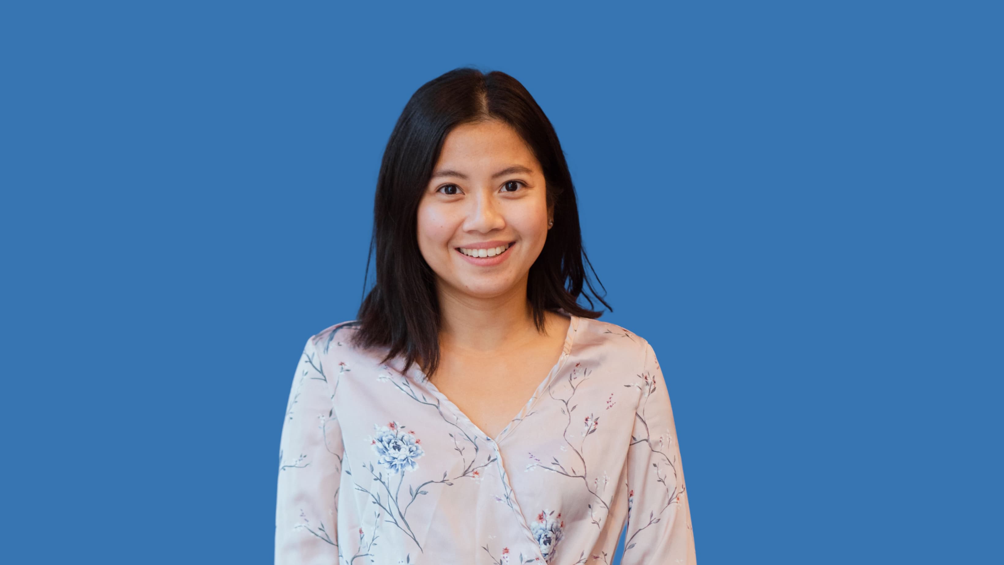 PortrÀt einer lÀchelnden Frau vor blauem Hintergrund