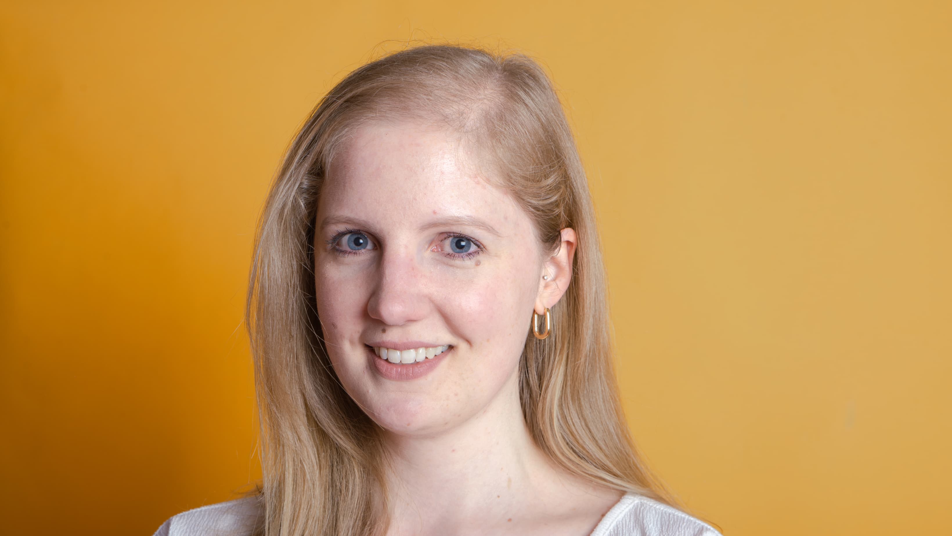 PortrÀt einer lÀchelnden jungen Frau vor orangefarbenem Hintergrund