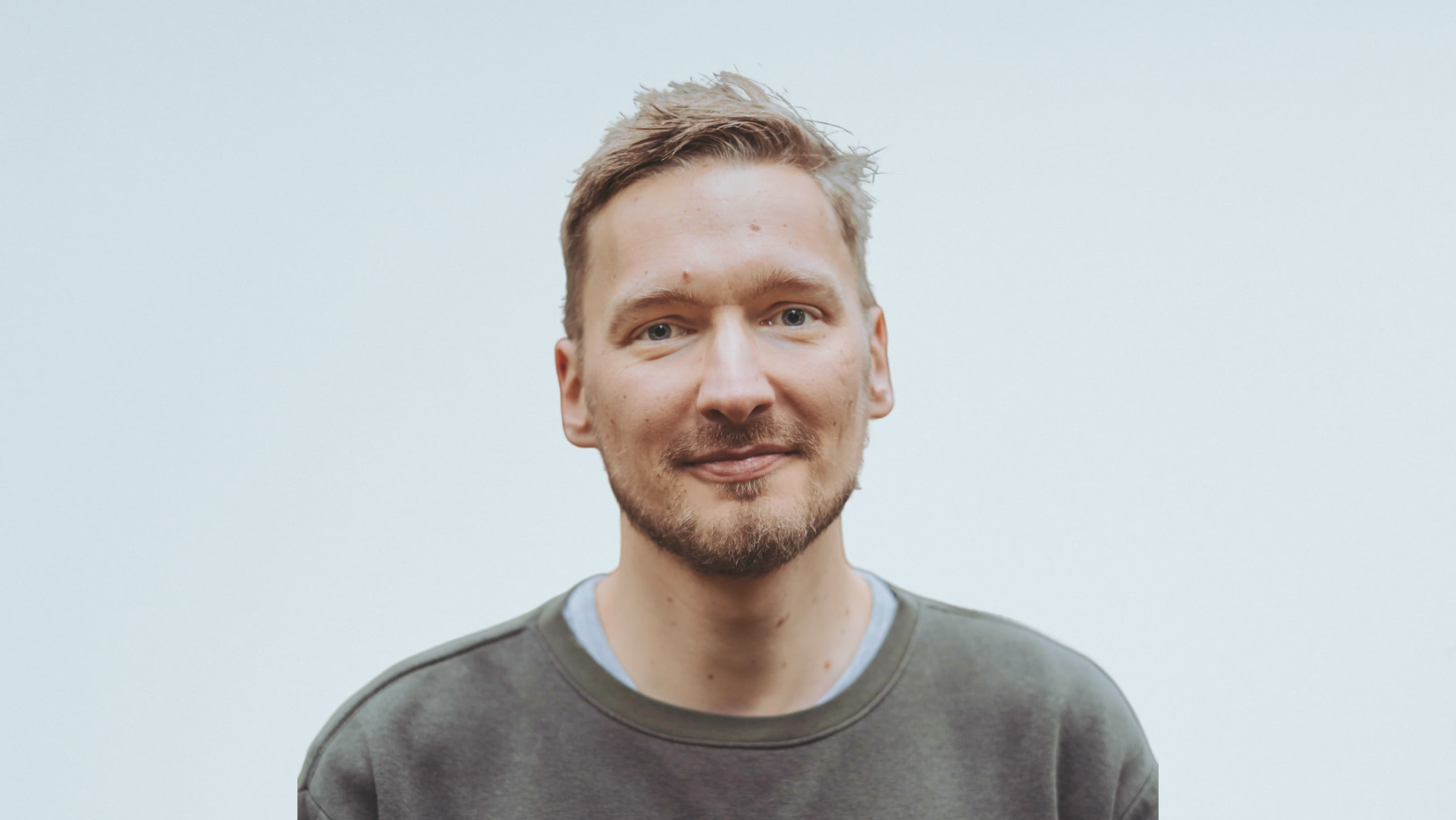 PortrÀt eines lÀchelnden Mannes vor einem hellen Hintergrund