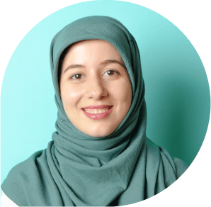 Portrait of a smiling woman wearing a green hijab against a blue background