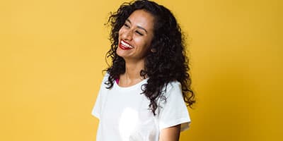 Smiling woman with curly hair against yellow background