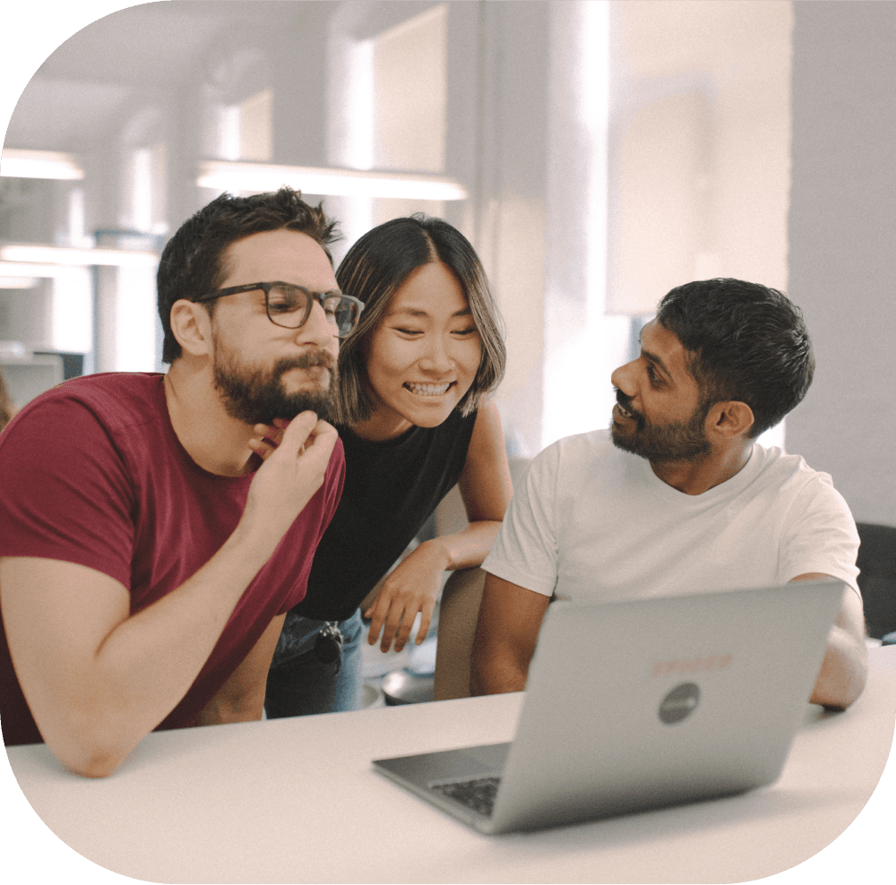Three people looking at a laptop together.