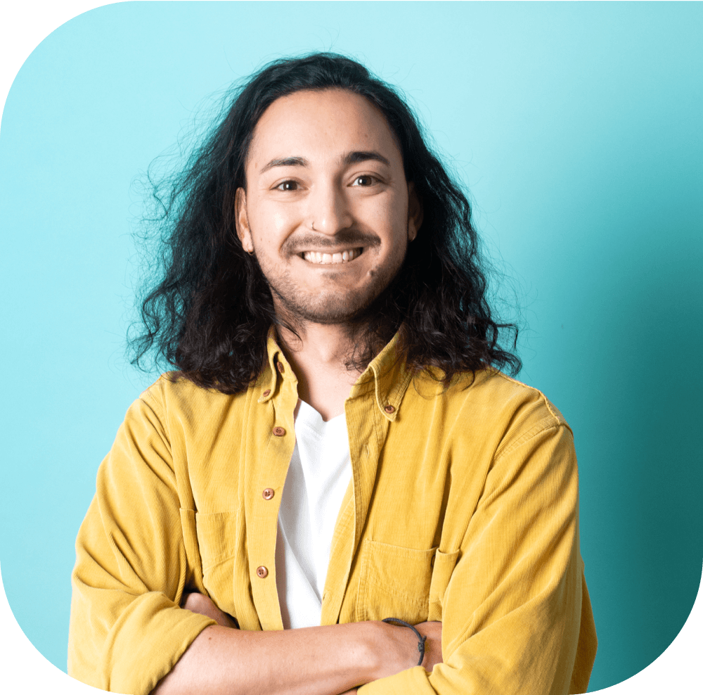 Portrait of a smiling man with long hair against a blue background.